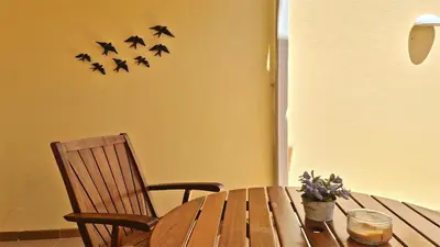 a wooden table with a chair and birds on the wall at Villa Nuki- CleverDetails, quiet location, sleeps 8, private pool in Vilamoura