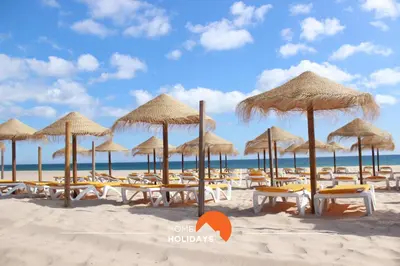 a beach with chairs and umbrellas on the sand at #172 Falésia Beach by Home Holidays in Albufeira