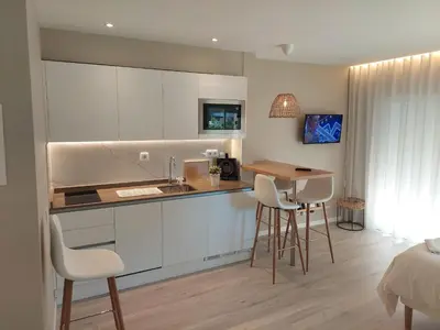a kitchen with white cabinets and a table and chairs at Impervila 201 in Vilamoura