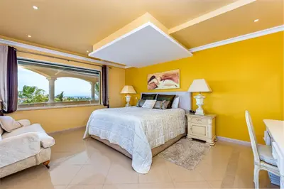 a bedroom with yellow walls and a bed and a window at Villa Casa do Monte in Albufeira