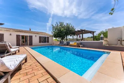 a swimming pool in a backyard with a villa at Villa Algarve 4 Ensuite Bedrooms, Private Swimming Pool, Beautiful Gardens with water features and natural Bio Pool in Almancil