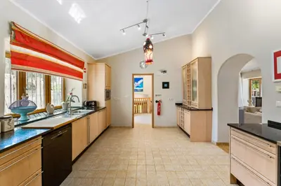a large kitchen with wooden cabinets and a tile floor at Villa Algarve 4 Ensuite Bedrooms, Private Swimming Pool, Beautiful Gardens with water features and natural Bio Pool in Almancil