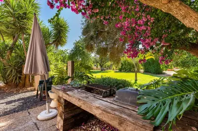 a garden with a wooden table and an umbrella at Villa Algarve 4 Ensuite Bedrooms, Private Swimming Pool, Beautiful Gardens with water features and natural Bio Pool in Almancil