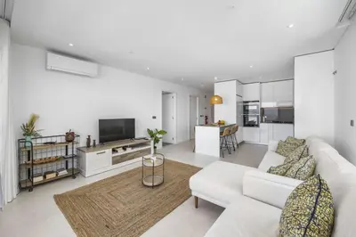 a living room with white furniture and a kitchen at Terraços de Quarteira Ethnic by Real Properties in Quarteira