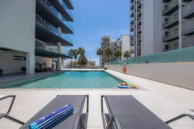 a swimming pool with two lounge chairs and a pool noodle in a building at Terraços de Quarteira Ethnic by Real Properties in Quarteira