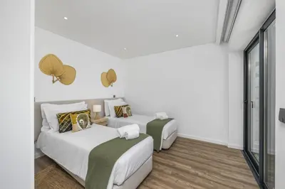 two beds in a room with white walls and wood floors at Terraços de Quarteira Ethnic by Real Properties in Quarteira