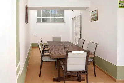 a dining room with a wooden table and chairs at Jardins da Galé Beach House in Albufeira