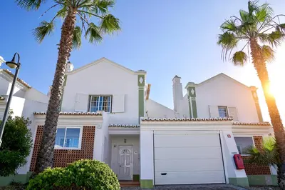 a white house with palm trees and a garage at Jardins da Galé Beach House in Albufeira