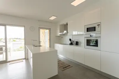 a white kitchen with white cabinets and a large window at Glamour Apartment With Pool in Albufeira