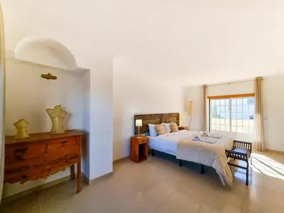 a bedroom with a bed and a table and a window at FLH Quinta das Salinas Triplex with Balcony in Vale do Lobo