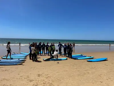 a group of people standing on a beach with surfboards at Varanda para o Mar in Albufeira