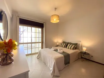 a white bedroom with a bed and a window at Vilamoura Garden View 2 With Pool by Homing in Vilamoura