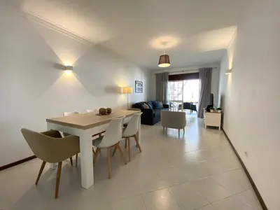 a dining room and living room with a table and chairs at Vilamoura Garden View 2 With Pool by Homing in Vilamoura