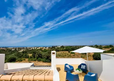 a view from the roof of a house with blue chairs and an umbrella at FLH Albufeira Ocean View House with Garden & Pool in Albufeira
