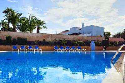 a large swimming pool with blue chairs and a swimming pool at FLH Albufeira Ocean View House with Garden & Pool in Albufeira