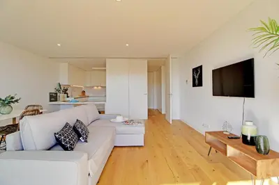 a living room with a white couch and a tv at White & Nature Apartment in Vilamoura