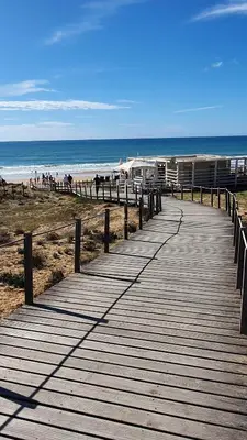 a wooden boardwalk leading to a beach with people on it at Apartamento do Pinhal - By Dalma Portuguesa in Albufeira