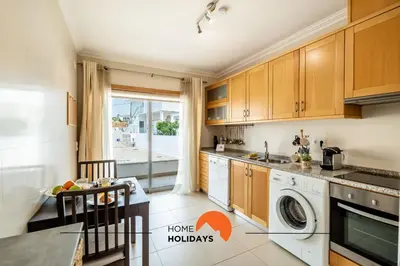 a kitchen with wooden cabinets and a table with a dining room at #160 V3 Vila Branca 92 by Home Holidays in Albufeira