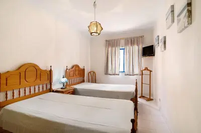 a bedroom with two beds and a window at Apartamento T1 Edisol in Quarteira