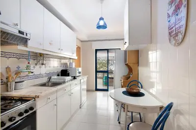 a kitchen with white cabinets and a table in it at Apartamento T1 Edisol in Quarteira