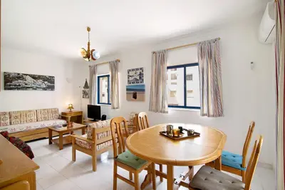 a living room with a table and chairs and a couch at Apartamento T1 Edisol in Quarteira