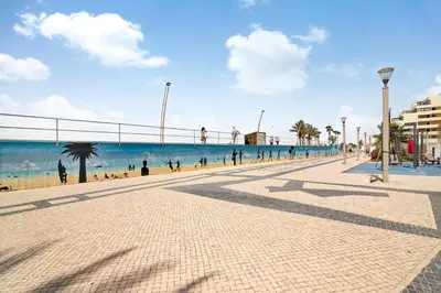 a sidewalk next to a beach with people on it at Apartamento T1 Edisol in Quarteira