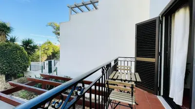 a balcony with a wooden bench and a black shutter at Neridas Villa by Check-in Portugal in Quarteira