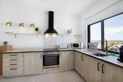 a kitchen with wooden cabinets and a sink and a window at Lindo T2 com vista mar in Quarteira