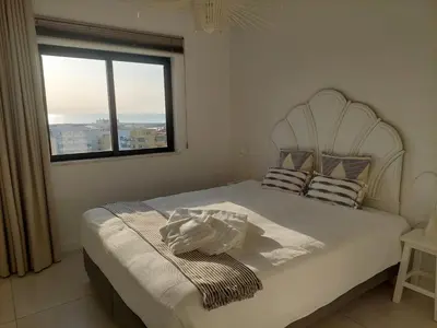 a bedroom with a white bed with a window at Lindo T2 com vista mar in Quarteira