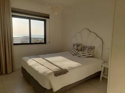 a bedroom with a bed with a large window at Lindo T2 com vista mar in Quarteira