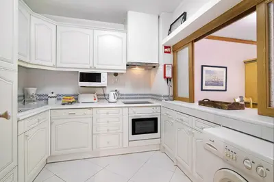 a white kitchen with white cabinets and appliances at T2 com piscina centro Vilamoura in Vilamoura