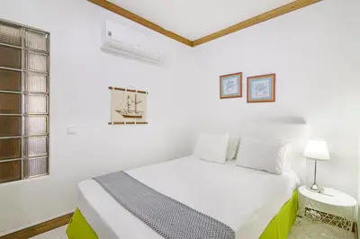 a white bedroom with a bed and a window at T2 com piscina centro Vilamoura in Vilamoura