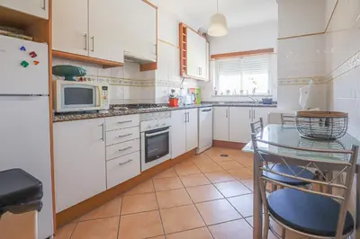 a kitchen with white cabinets and a table and a microwave at Apart ALGARVE - Piscina - BY BEDZY in Albufeira