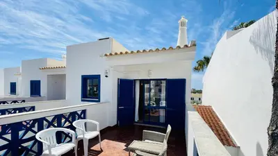 a white house with blue doors and chairs on a balcony at Jardim da Oura by Check-in Portugal in Albufeira