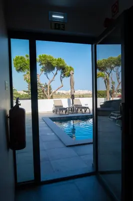 a door leading to a pool with a statue in the distance at Ria Formosa Guest House in Faro