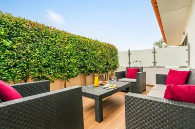 a patio with chairs and a table with red pillows at Sunshine Holiday House in Quarteira