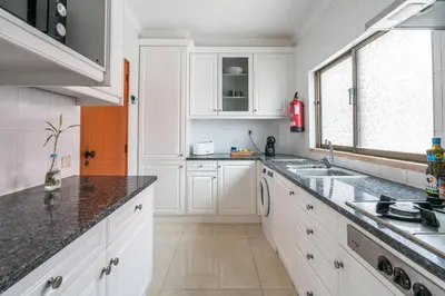 a kitchen with white cabinets and a sink and a window at Sunshine Holiday House in Quarteira