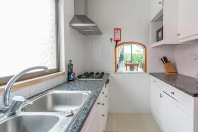 a white kitchen with a sink and a window at Sunshine Holiday House in Quarteira
