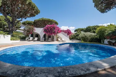 a swimming pool in front of a villa at Traditional 3 bedroom villa with great pool in the heart of Vale do Lobo in Vale do Lobo