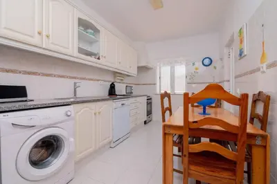 a kitchen with a washing machine and a table and chairs at Galé Catia by Innkeeper in Guia