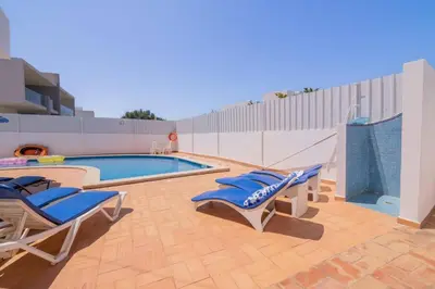 a swimming pool with blue lounge chairs next to a building at Galé Catia by Innkeeper in Guia