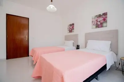 two beds in a white room with pink sheets at Galé Igor by Innkeeper in Guia