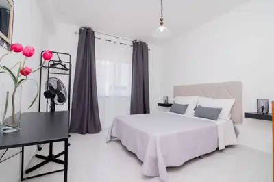 a white bedroom with a bed and a table with flowers at Galé Igor by Innkeeper in Guia