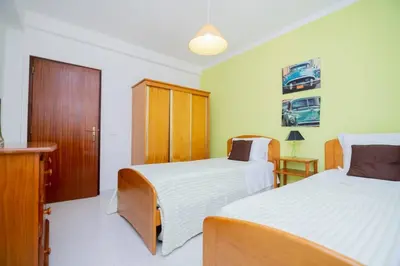 a bedroom with two beds and a wooden cabinet at Galé Magda by Innkeeper in Guia