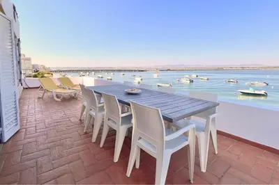 a table and chairs on a patio with a view of the water at Beach House on Faro Island with a Dreamy Terrace and 7 Beds for the Perfect Escape in Faro
