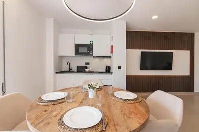 a dining room with a wooden table with white plates at Apartamento em Albufeira - Condomínio com Piscina in Albufeira