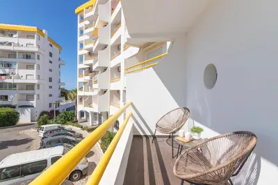 a balcony with two chairs and a building at Apartamento em Albufeira - Condomínio com Piscina in Albufeira