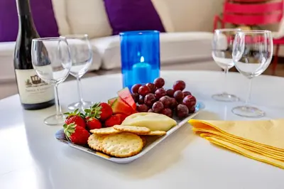 a plate of fruit and cheese on a table with wine glasses at Central Algarve Duplex Retreat with Garden & Pool in Quarteira