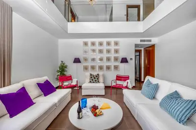 a living room with white furniture and purple pillows at Central Algarve Duplex Retreat with Garden & Pool in Quarteira
