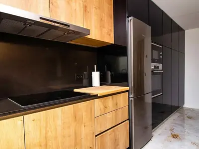 a kitchen with wooden cabinets and a stainless steel refrigerator at Sea la Vie House by Stay ici Algarve Holiday Rental in Albufeira
